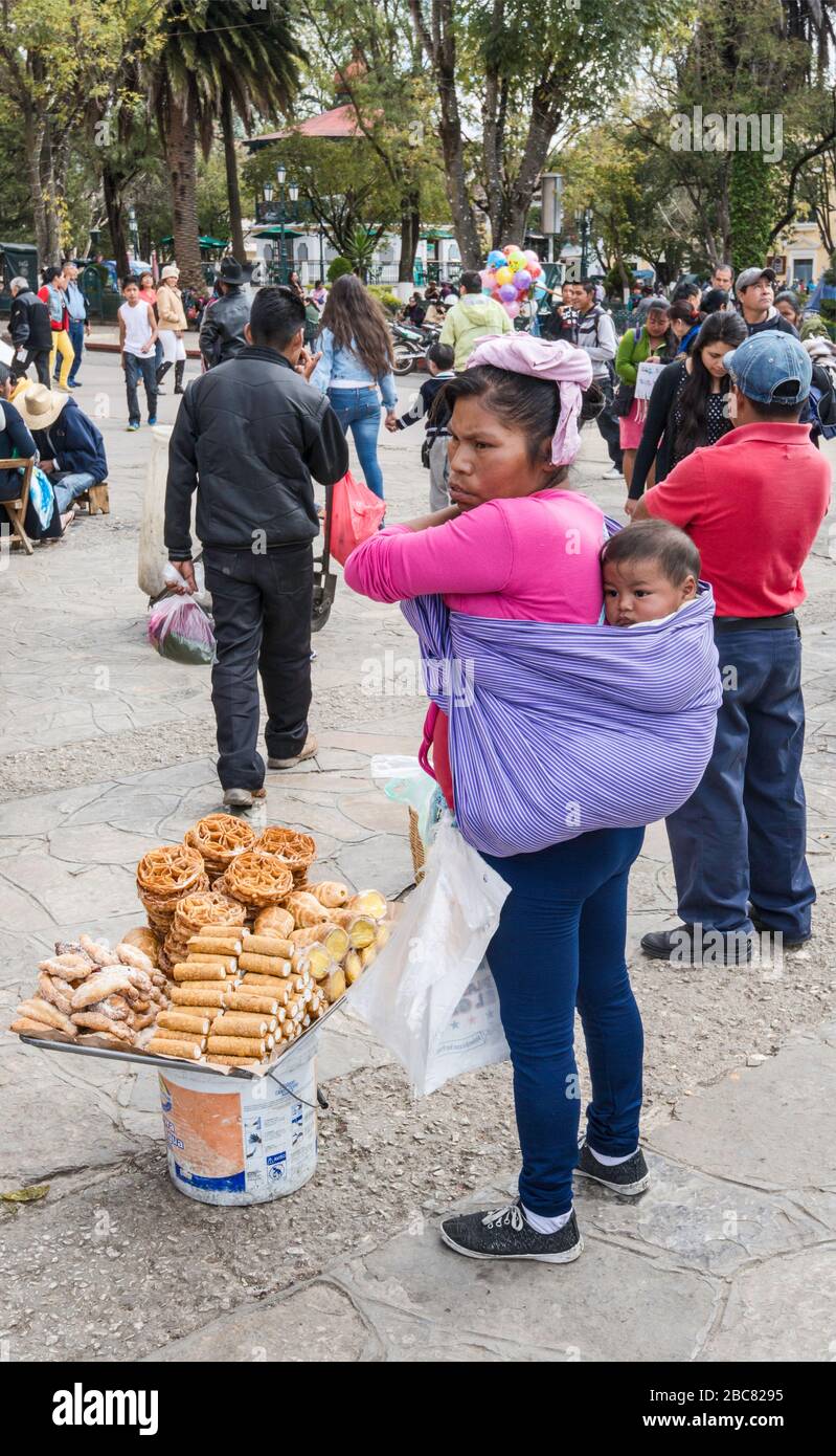 Maya mother holding her son, selling pastry at Plaza 31 de Marzo (zocalo) in San Cristobal de las Casas, Chiapas, Mexico Stock Photo