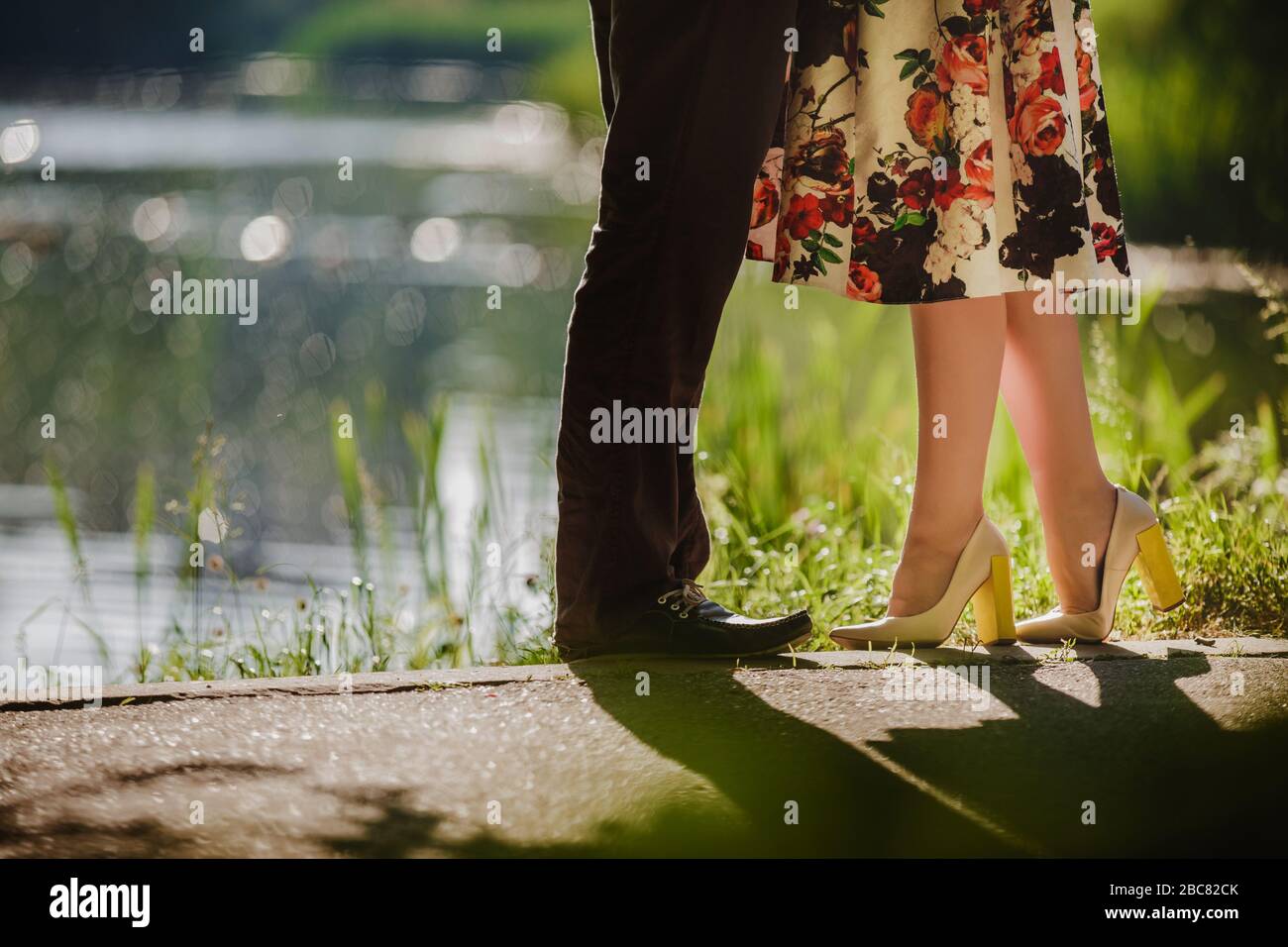 Couple kissing outdoors - Lovers on a romantic date at sunset,girls stands  on tiptoe to kiss her man - Close up on shoes Stock Photo - Alamy