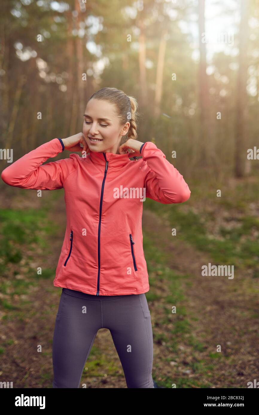 Fit healthy slender happy young woman outdoors at sunset walking along a forest trail backlit by the glow of the sun in spring Stock Photo