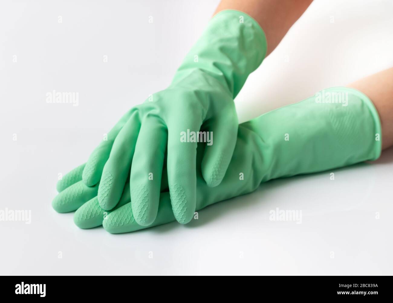 Hand in green latex dishwashing gloves on a white background Stock