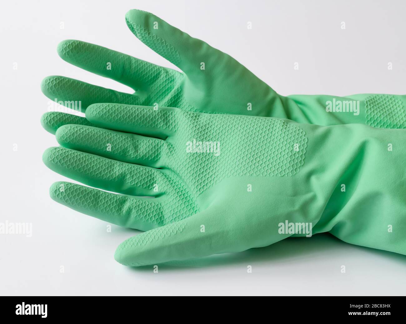 Hand in green latex dishwashing gloves on a white background Stock
