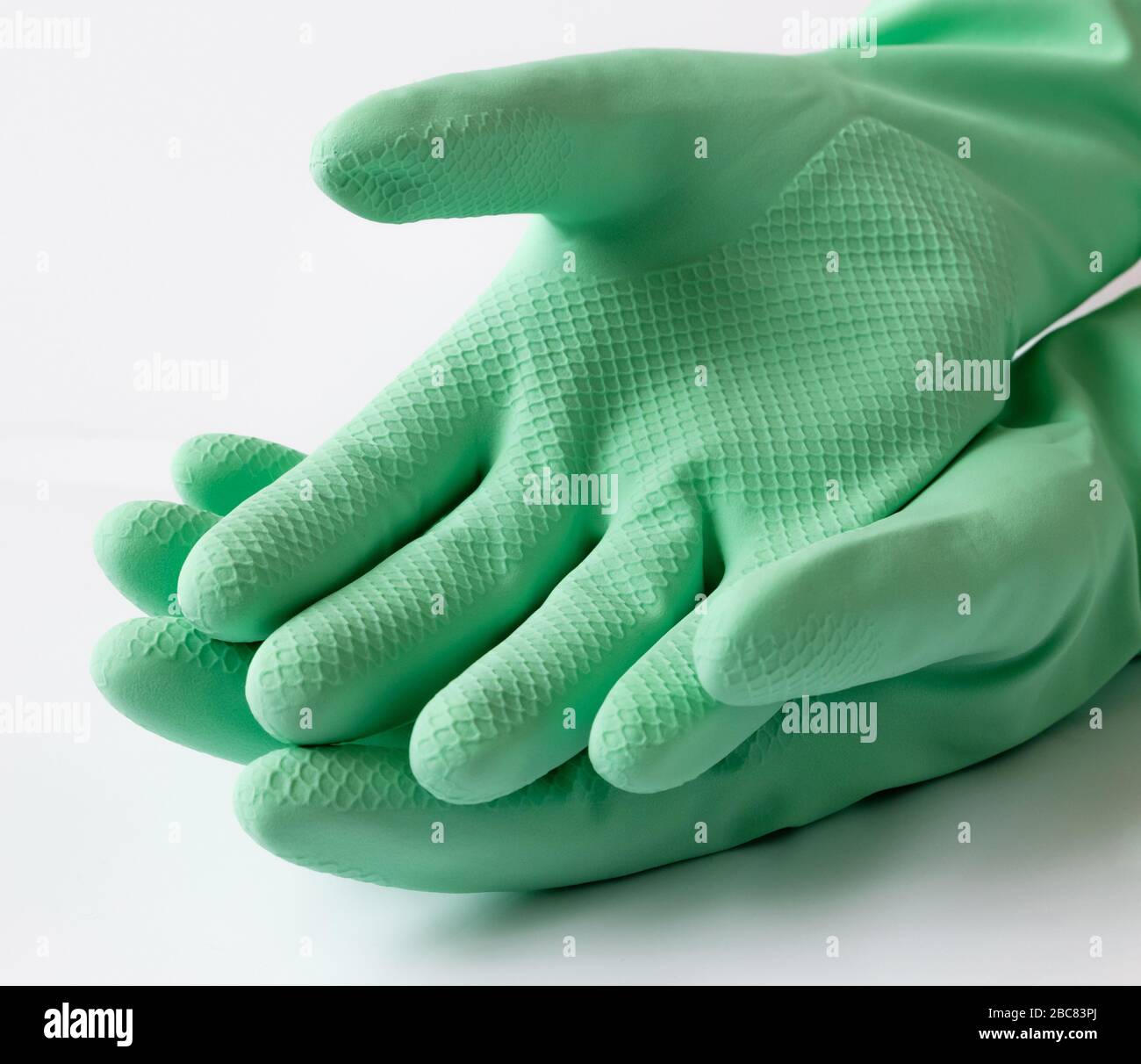 Hand in green latex dishwashing gloves on a white background Stock