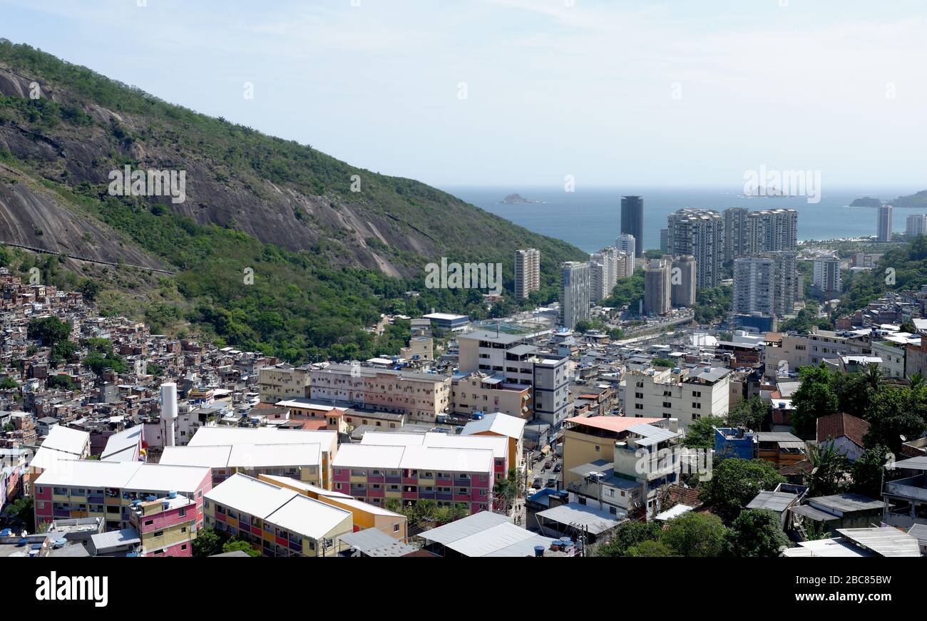 The over crowded Rochina favela in Rio De Janerio, Brazil, from high viewpoint with the Alantic ocean and prosperous Sao Conrado towering in front. Stock Photo