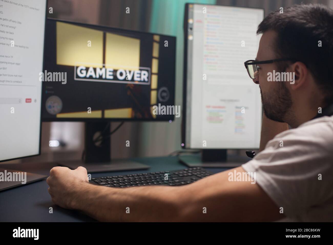 Young man keeping his fist tight after losing at online shooter games. Game over for gamer. Stock Photo