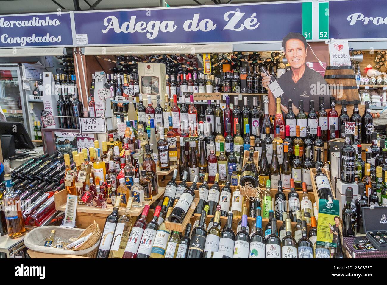 Bottles of wine on sale at stall in indoor market with Cliff Richard cutout, Loule, Algarve, Portugal Stock Photo