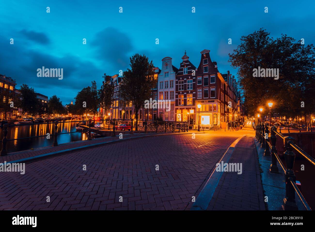 Amsterdam illuminated bridge with typical dutch houses in evening blue hour lights, Holland