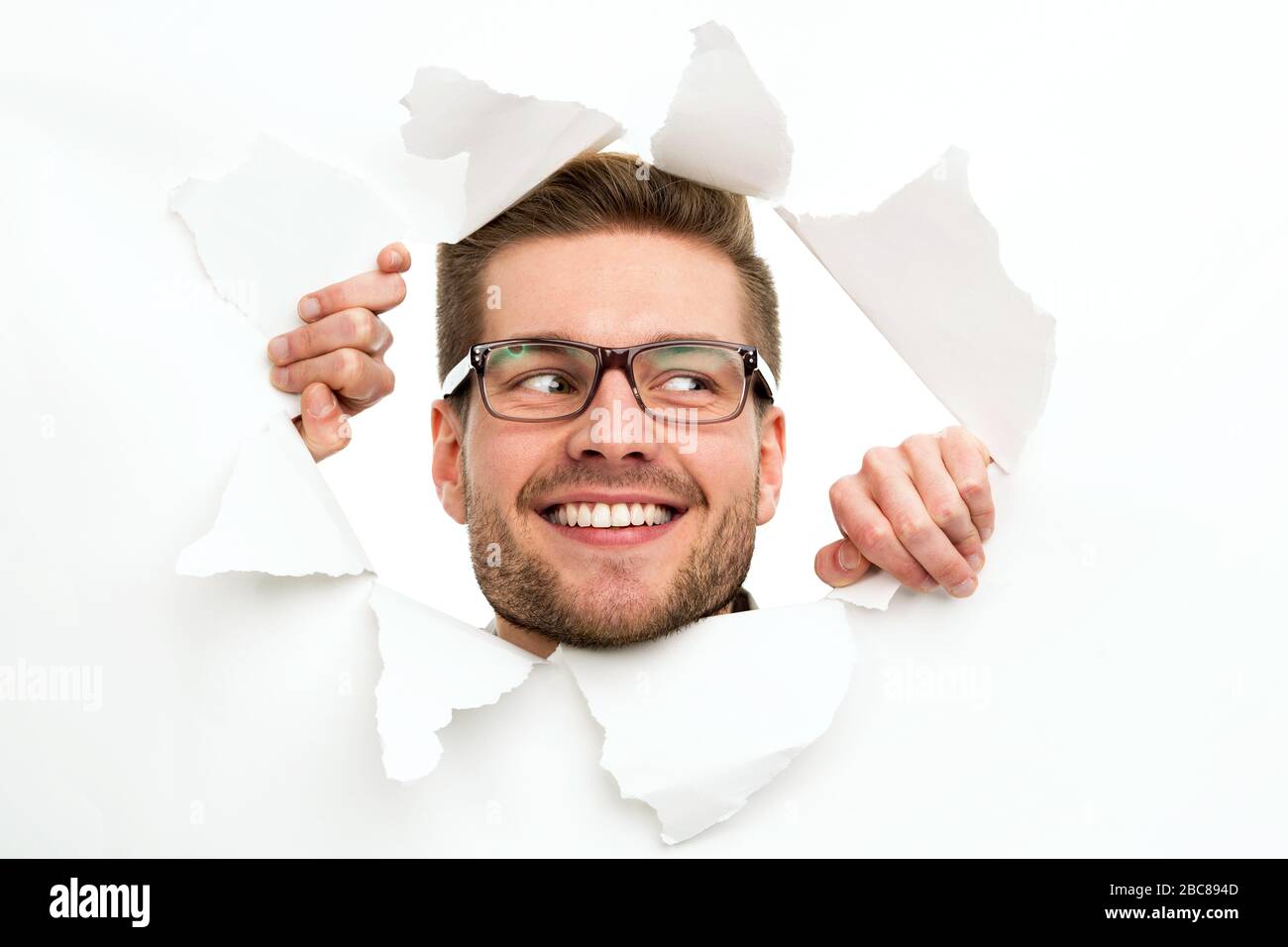 Man looking through hole in paper Stock Photo