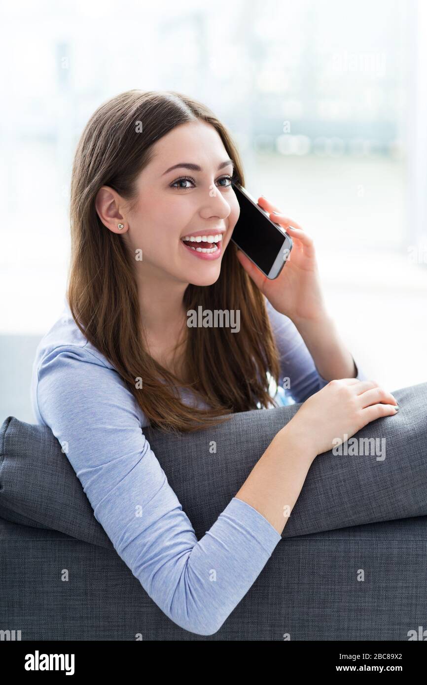 Woman using mobile phone on sofa Stock Photo