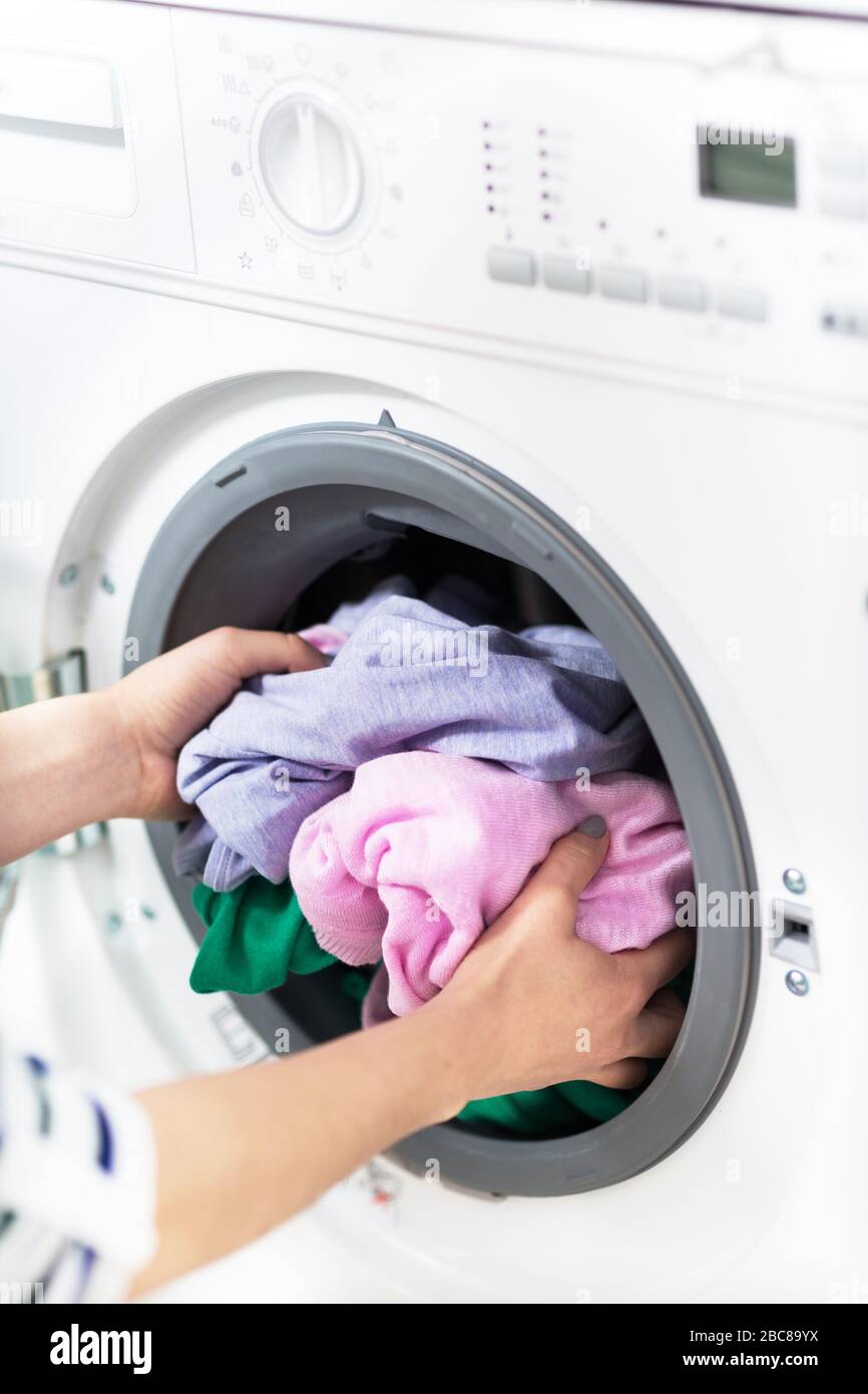 Woman Putting her Laundry into a Washing Machine Stock Photo
