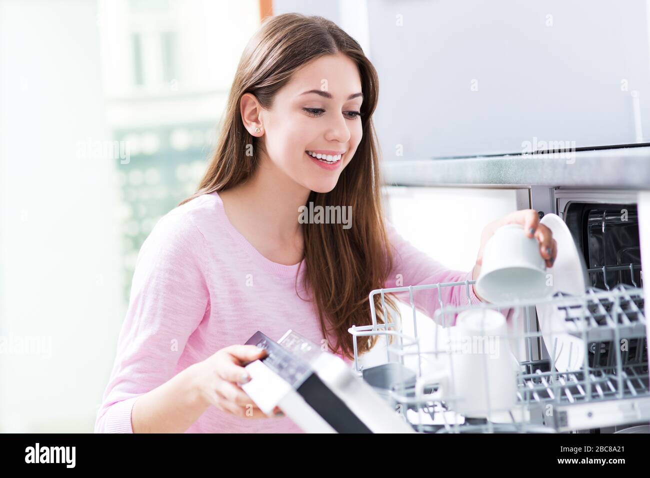Woman loading dishwasher Stock Photo
