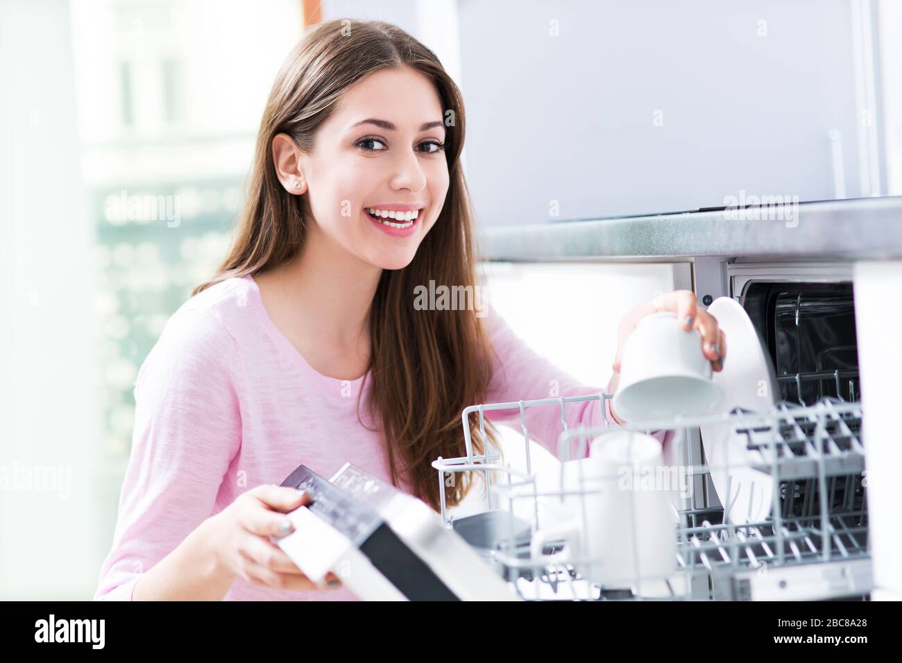Woman loading dishwasher Stock Photo