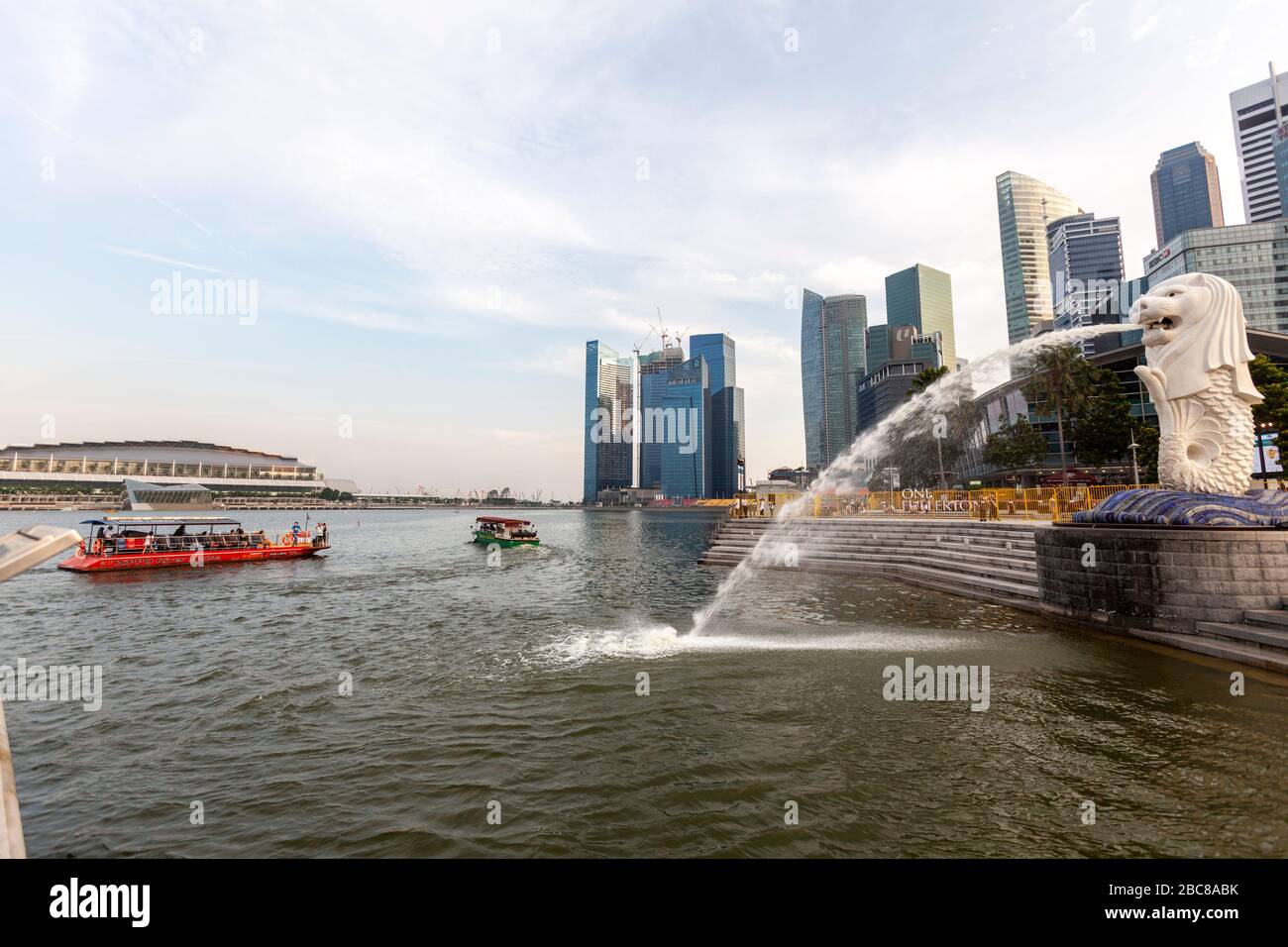 Boat of tourists looking The Merlion seen from its back with a view at the skyline, Singapore Stock Photo