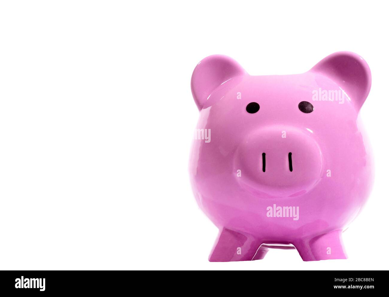 Horizontal shot of a pink piggy bank facing the camera on the right side of the picture.  Lots of copy space on the left side.  White background. Stock Photo