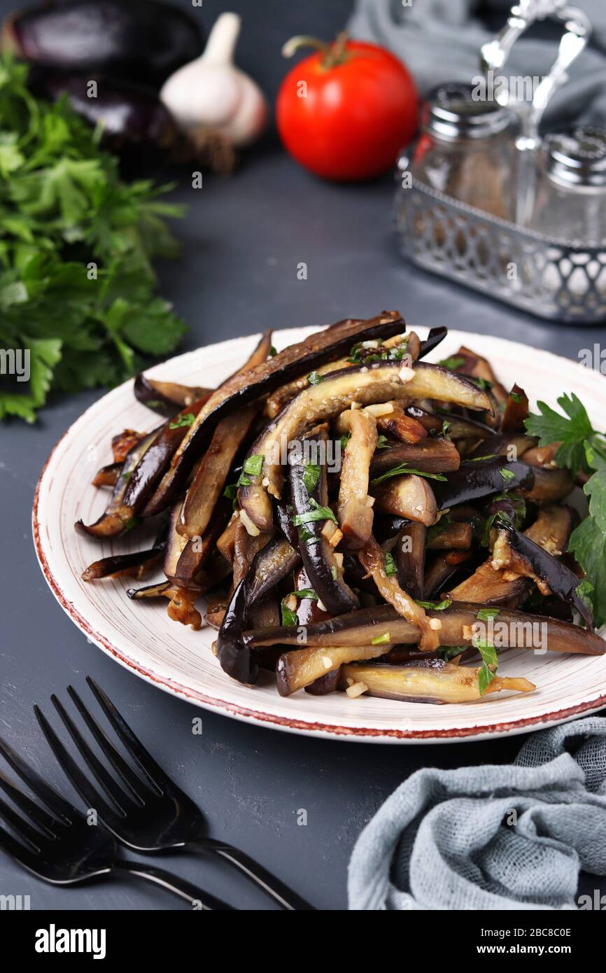 Fried eggplants with garlic and soy sauce, sliced in stripes, in a