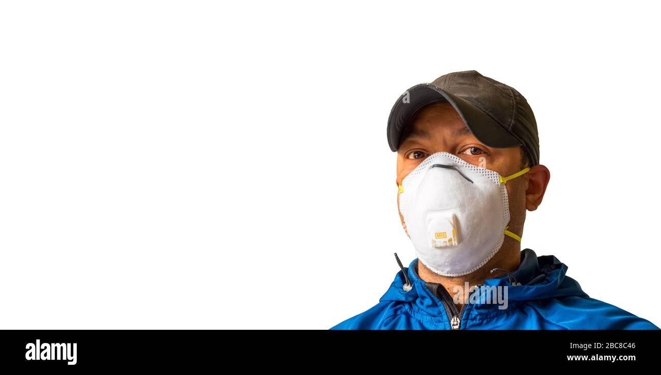 An adult male worker is wearing an N95 respirator mask and looking into the camera lens. White background for copy space. Stock Photo