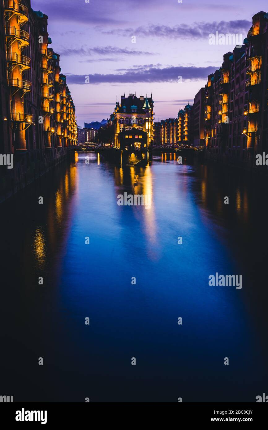 Blue hour in Warehouse District - Speicherstadt with lilac colored sky. Tourism landmark Wandrahmsfleet in twilight. Place is located in Port of Hambu Stock Photo