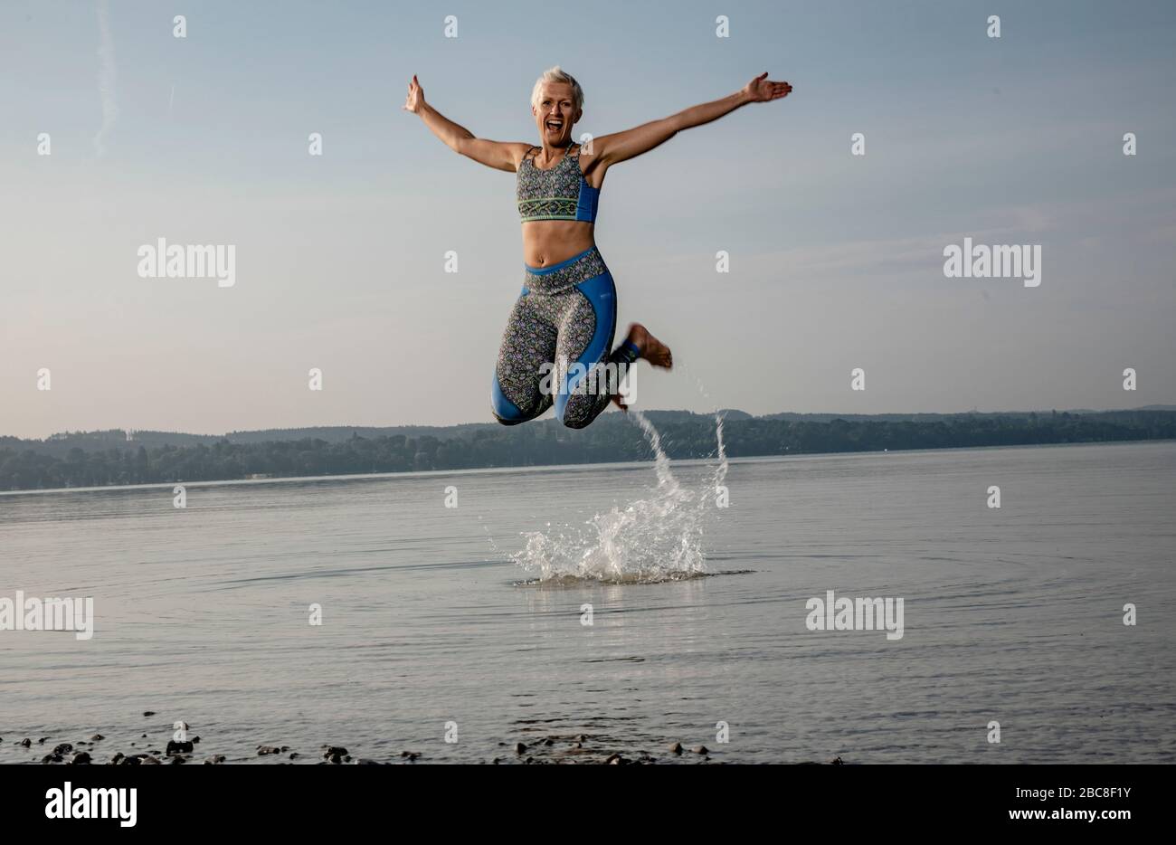 IKYA meditation, woman in sportswear cheerfully by the lake Stock Photo