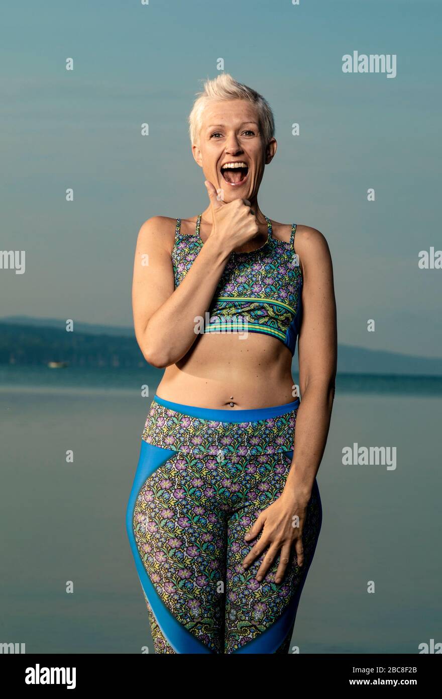 IKYA meditation, woman in sportswear cheerfully by the lake Stock Photo