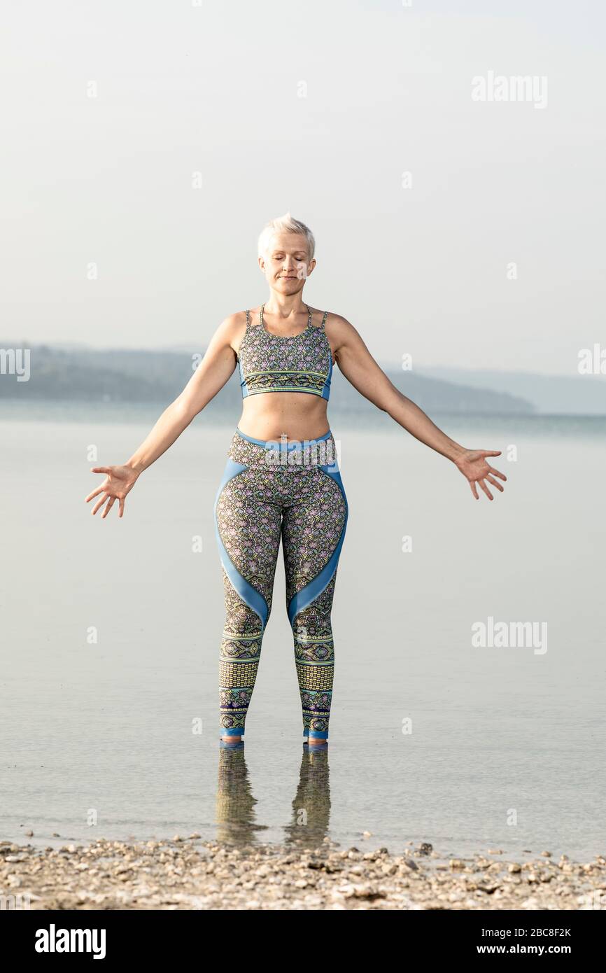 IKYA meditation, woman in sportswear cheerfully by the lake Stock Photo