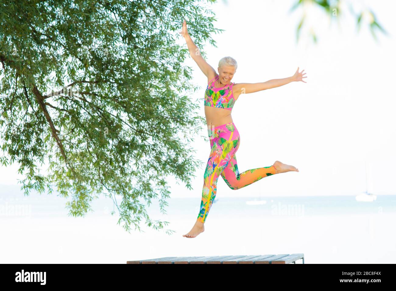 IKYA meditation, woman in sportswear cheerfully by the lake Stock Photo