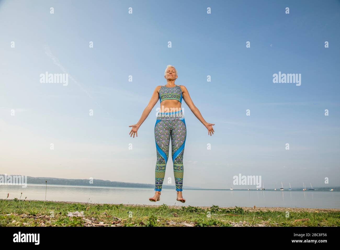 IKYA meditation, woman in sportswear cheerfully by the lake Stock Photo