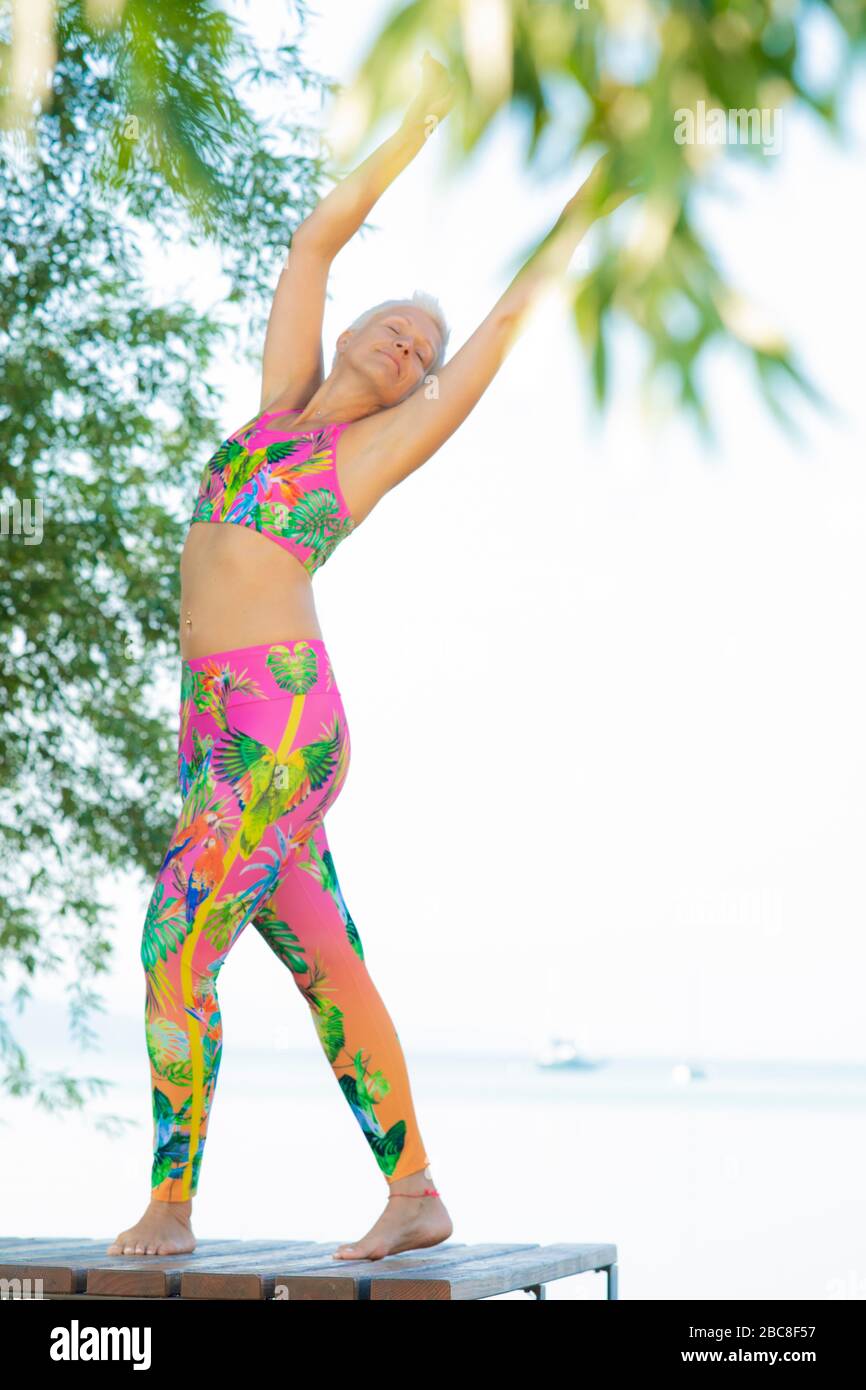 IKYA meditation, woman in sportswear cheerfully by the lake Stock Photo