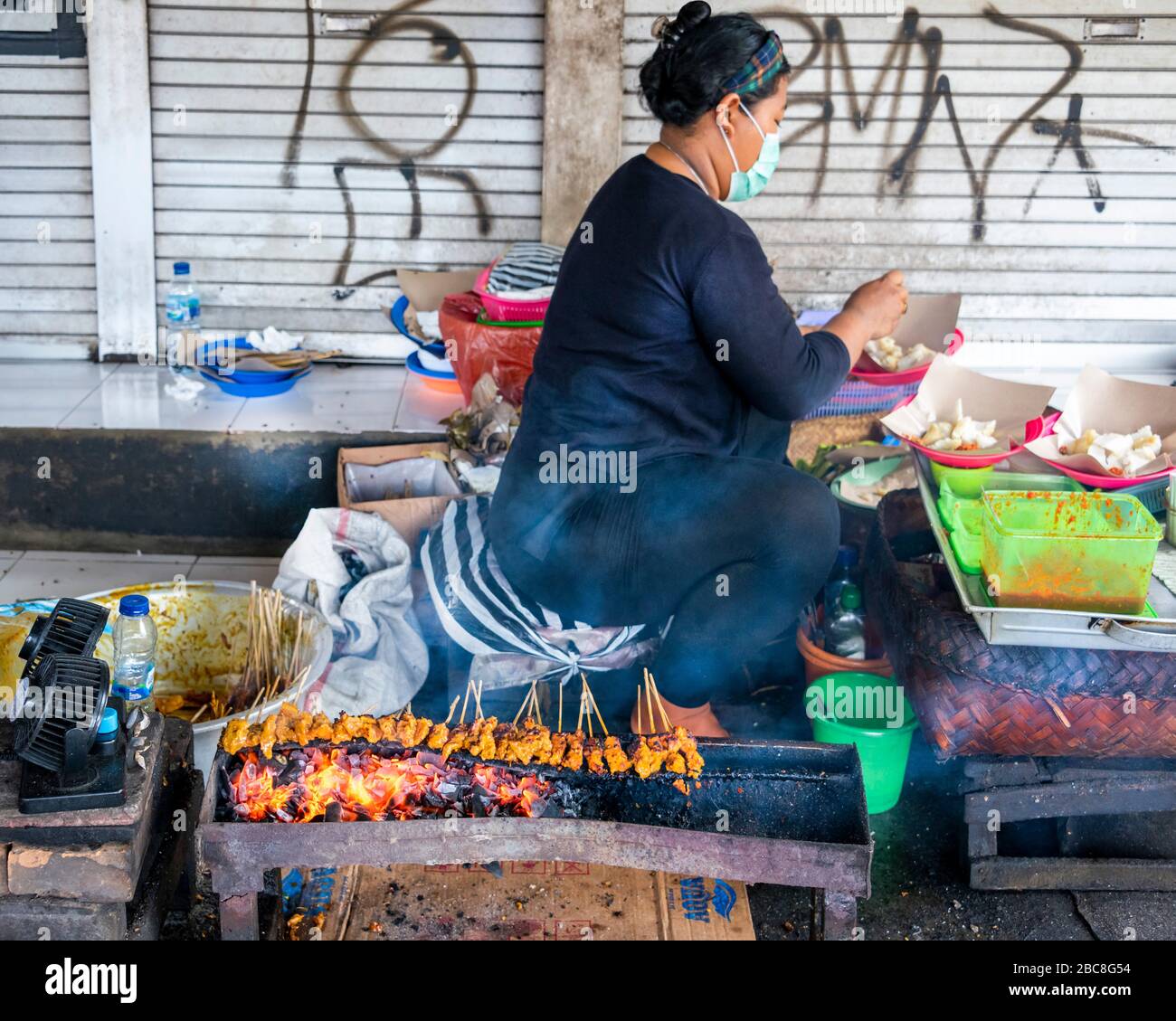 Horizontal view of a lady cooking sate on the side of the road in Bali. Stock Photo