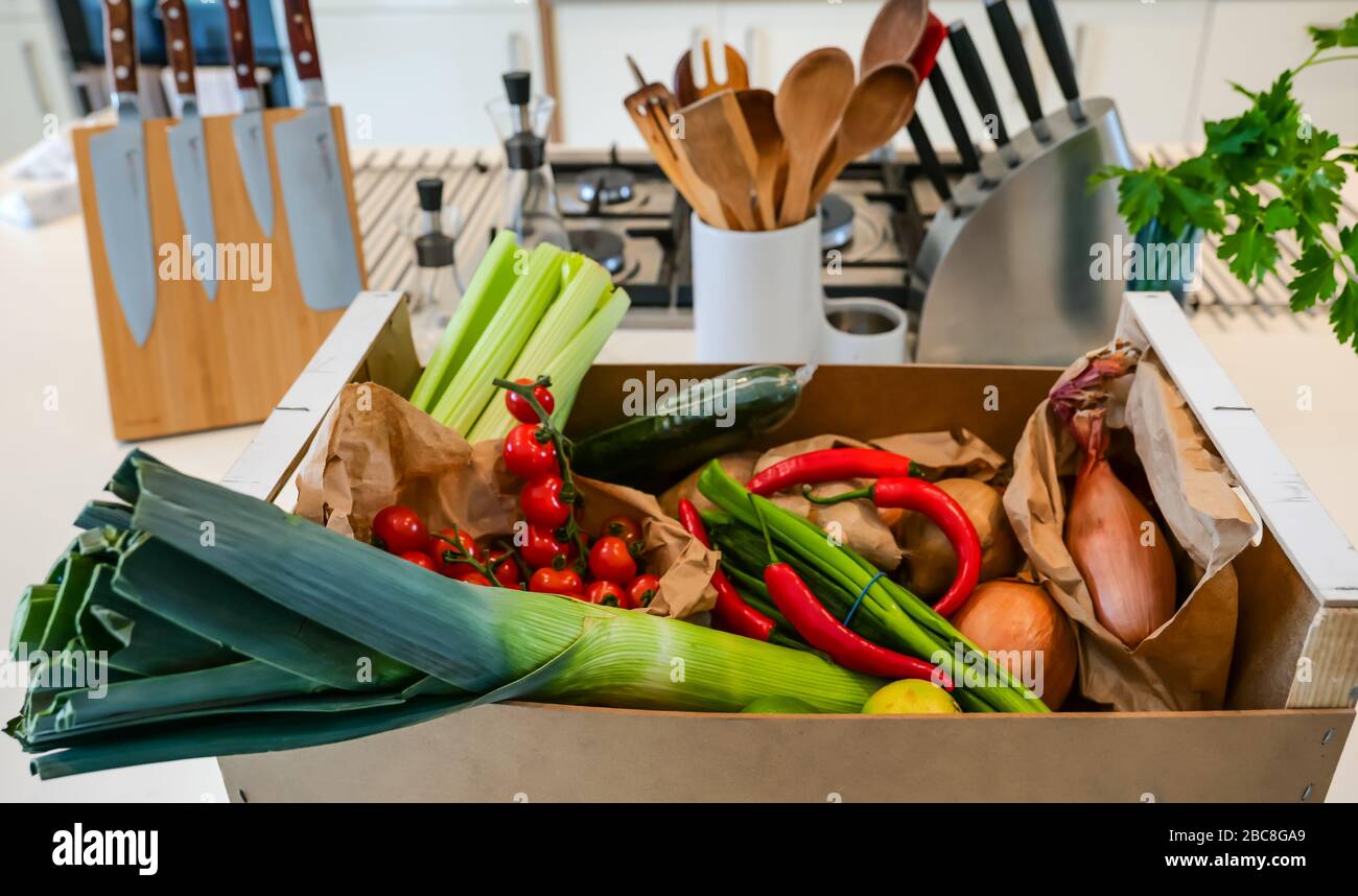 Local home delivery of fresh vegetables on kitchen counter: celery, cherry tomatoes, leek, onions, potatoes, red chillies, spring onions & limes Stock Photo