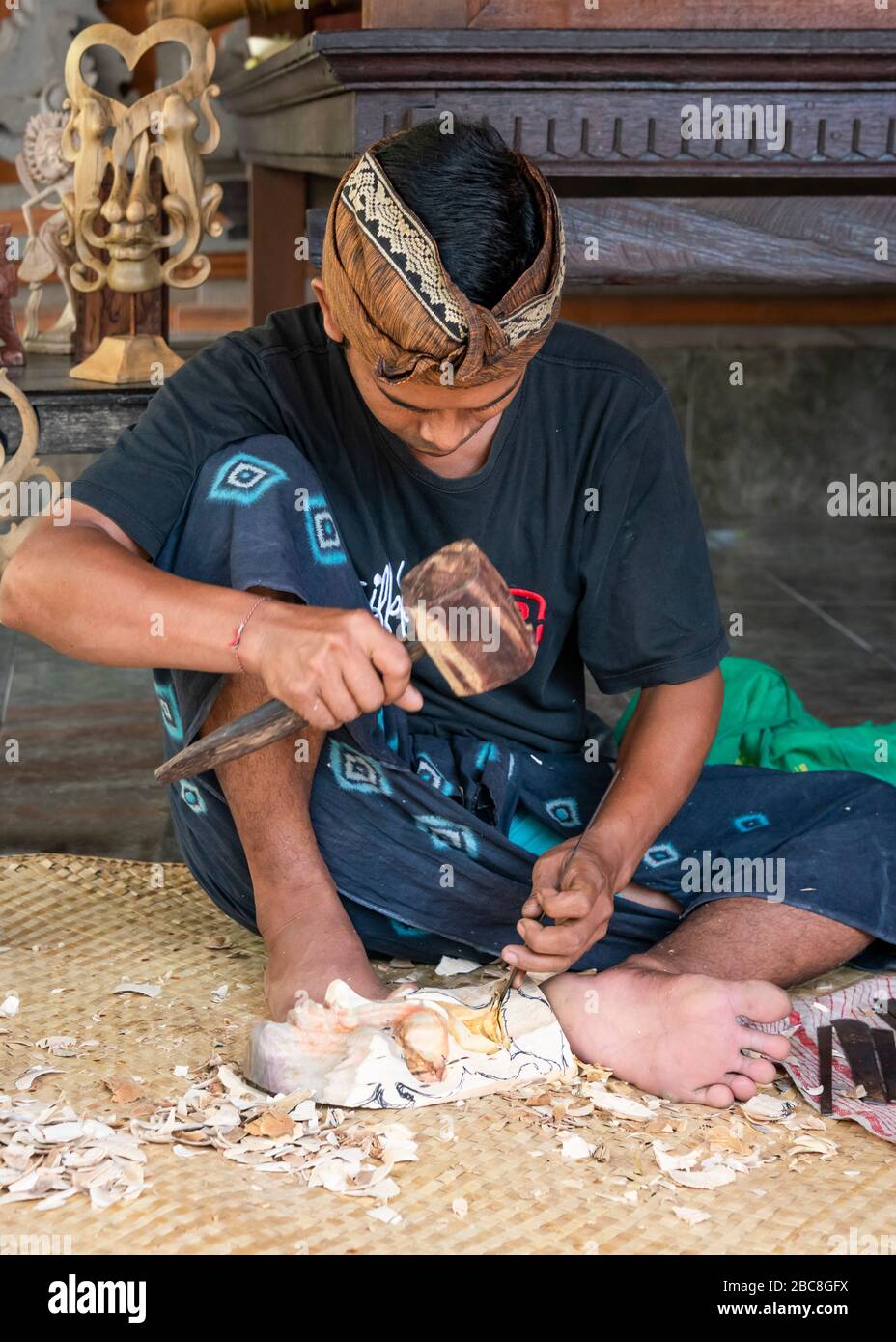 Vertical portrait of a man carving a wooden mask in Bali, Indonesia. Stock Photo