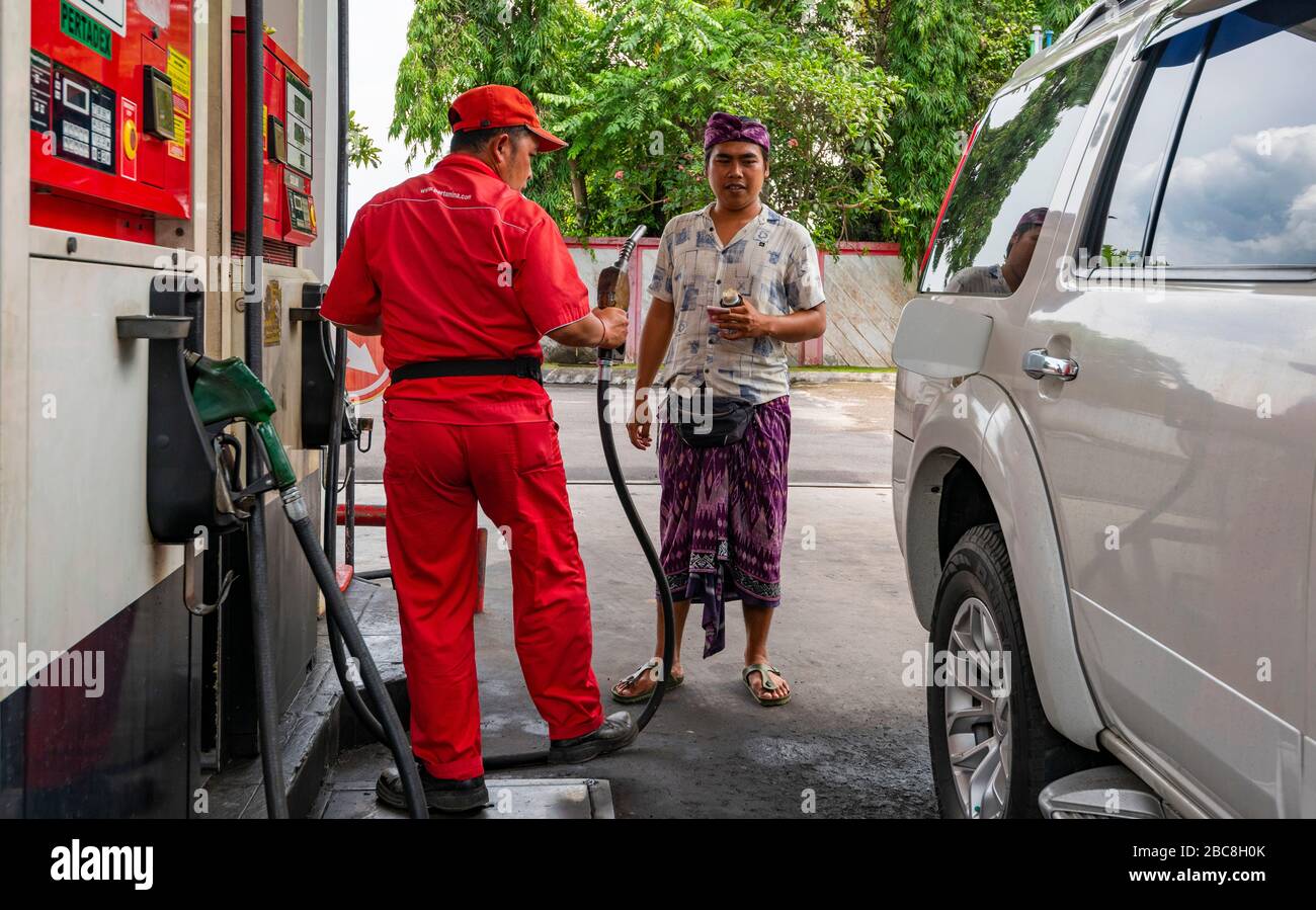 Horizontal view of a man having his car filled with petrol in Bali, Indonesia. Stock Photo