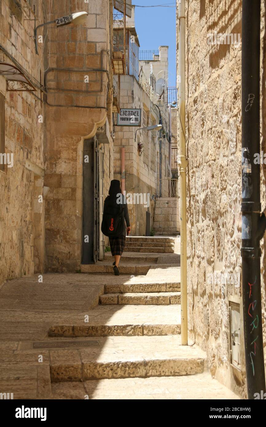 Israel, Jerusalem, woman runs through old town alley Stock Photo