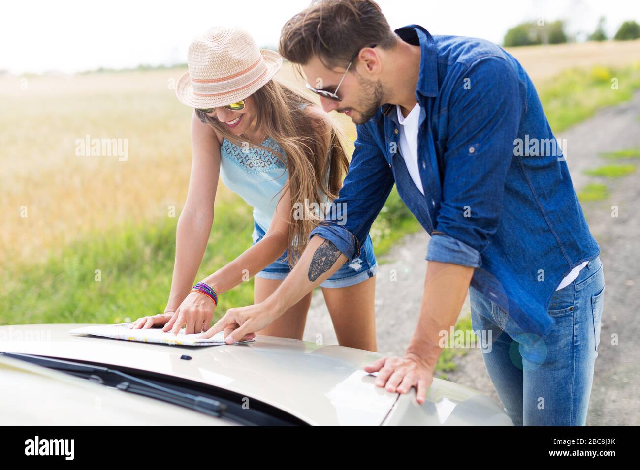 Couple reading a map while standing near convertible Stock Photo