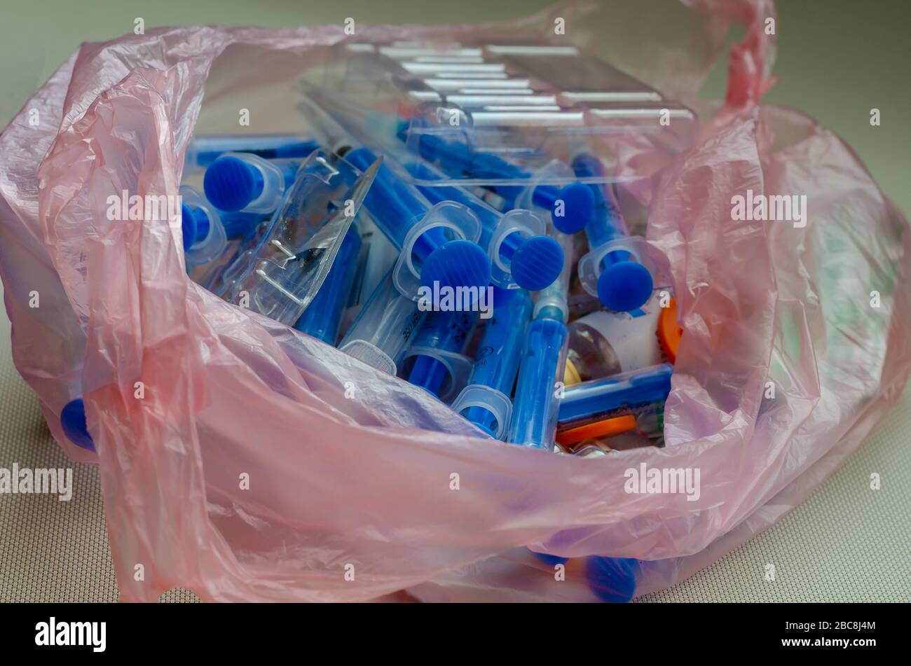 Used syringes, vials and ampoules in a bag. Plastic bag with medical waste. Medical instruments for disposal. Close-up. Selective focus. Stock Photo