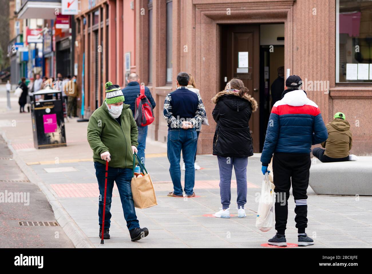 Glasgow, Scotland, UK. 3 April, 2020. Images from the south side of Glasgow at the end of the second week of Coronavirus lockdown. Customers queue to enter the Bank of Scotland branch on Victoria Road, Govanhill. Iain Masterton/Alamy Live News Stock Photo