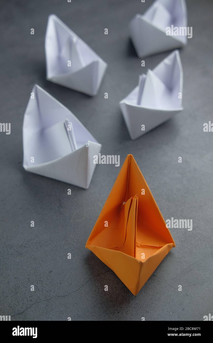 Leadership concept using orange paper ship among white. Stock Photo