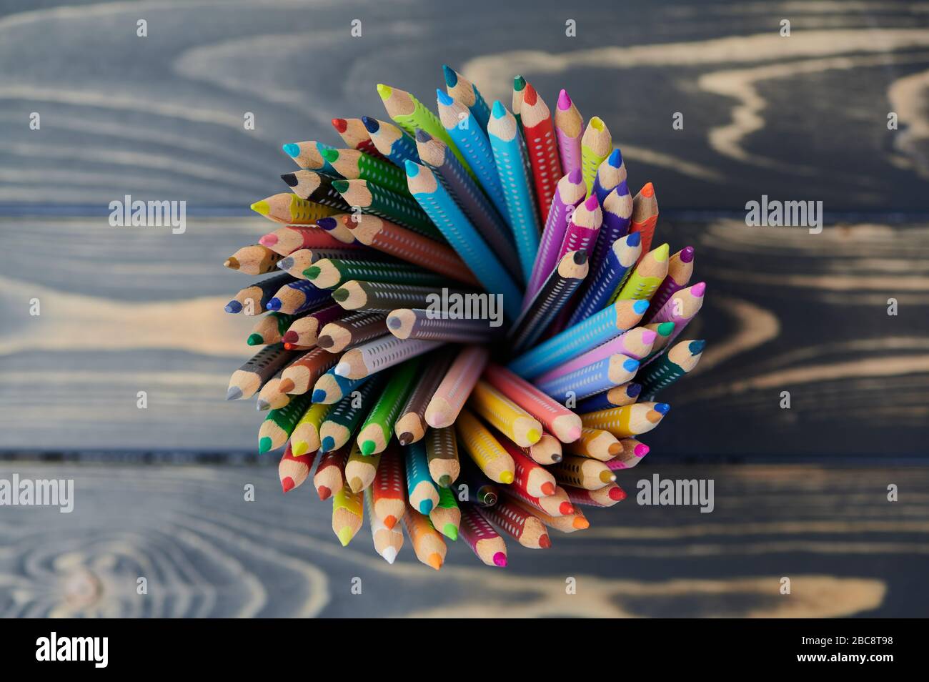 colored pencils in a pencil cup on wooden table, close up photo, view from above Stock Photo