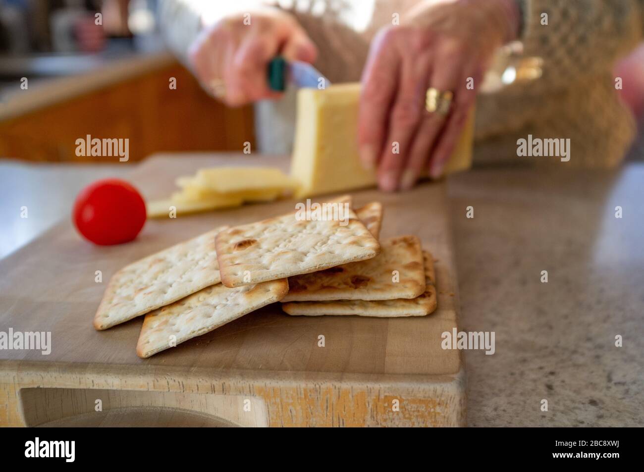 Crackers with cheese being sliced in the background Stock Photo