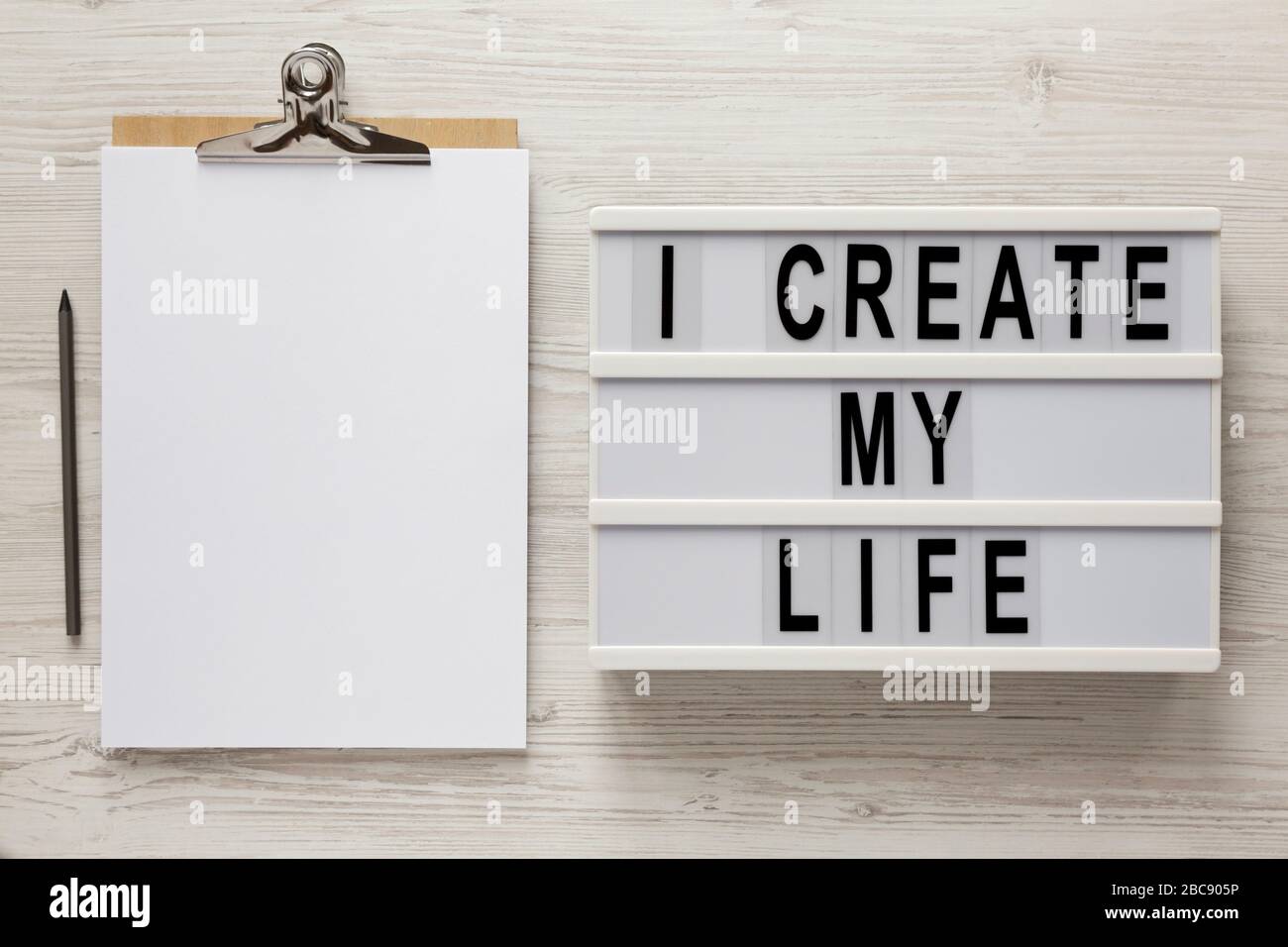 'I create my life' words on a lightbox, clipboard with blank sheet of ...