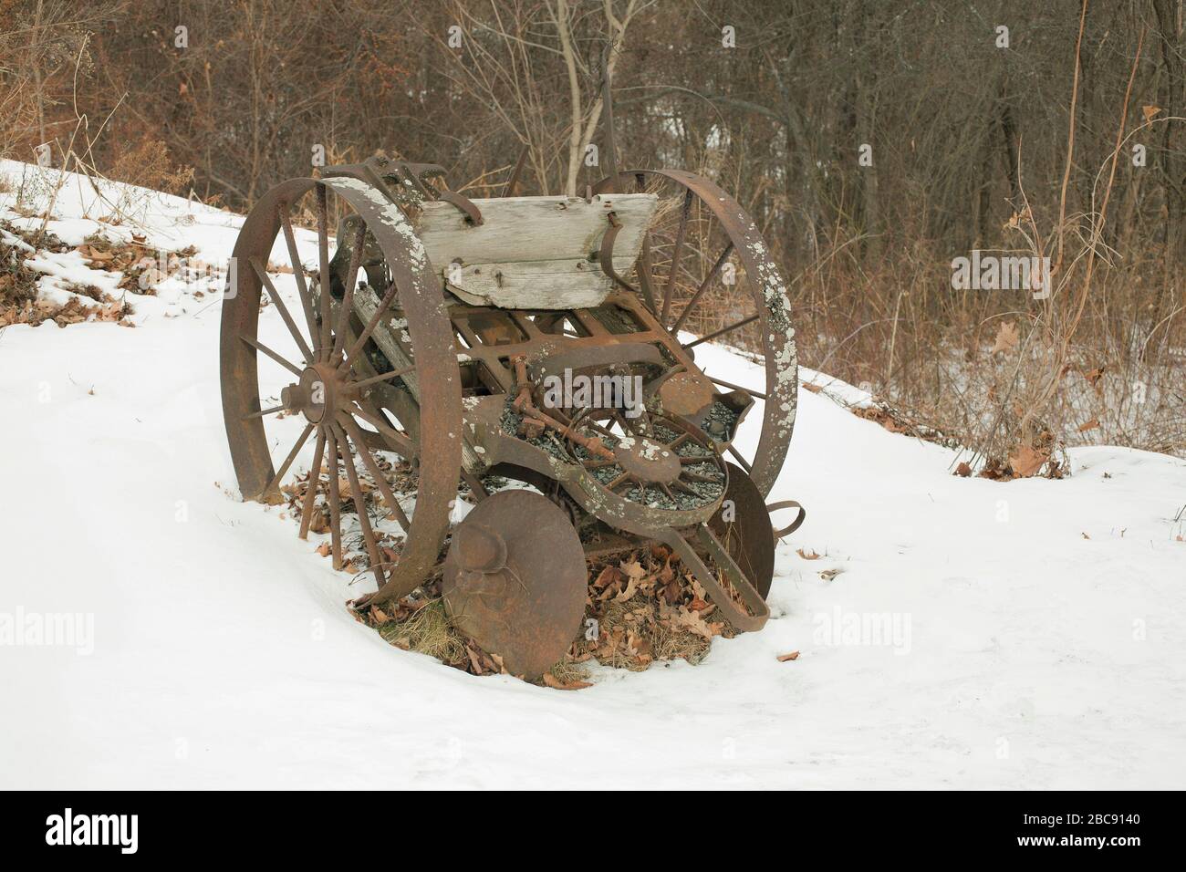 Vintage 100 year old potato planter sits idle on a snowy field in Massachusetts. Stock Photo