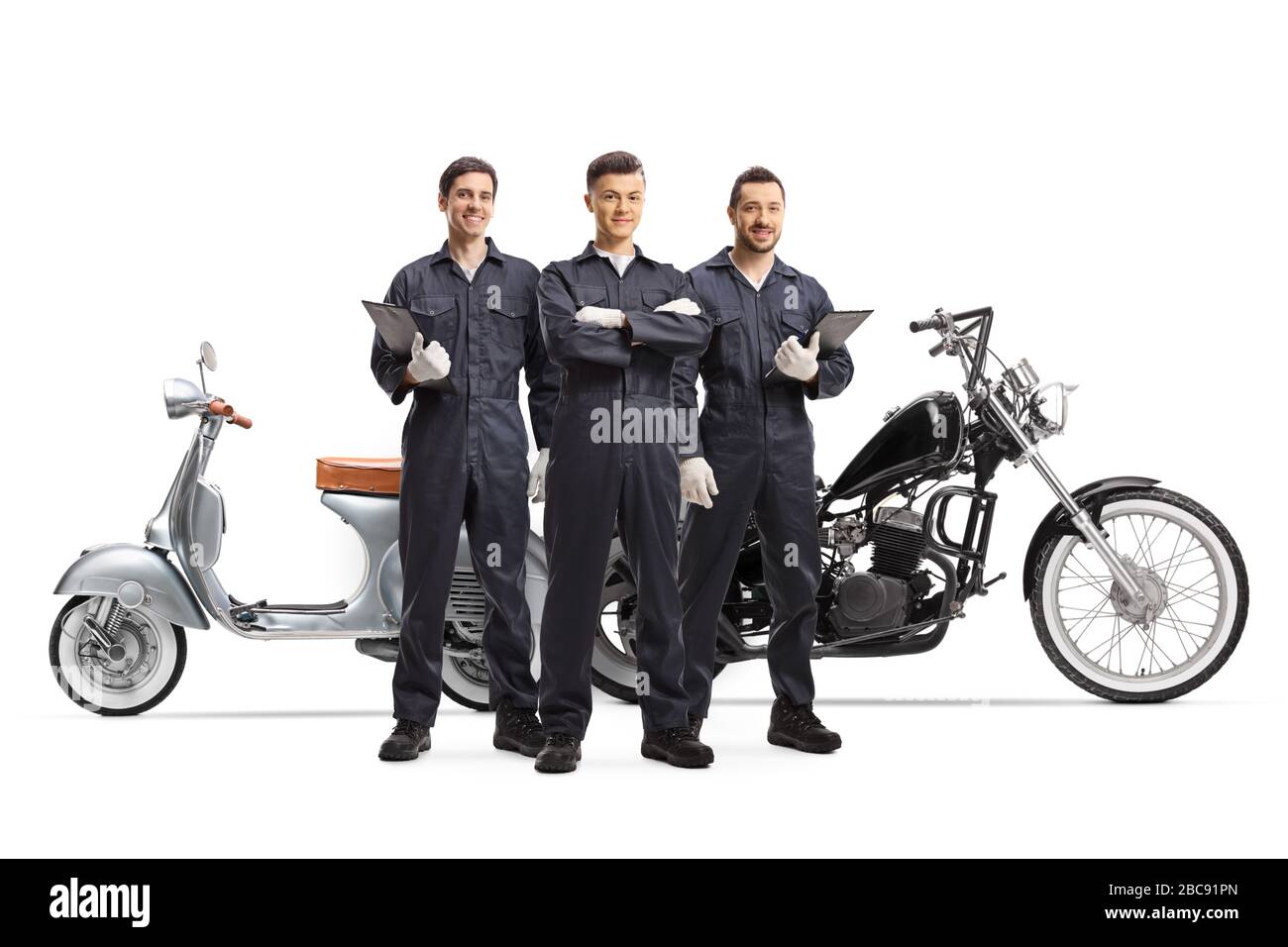 Full length portrait of motorcycle mechanic workers in uniforms posing next to motorbikes isolated on white background Stock Photo