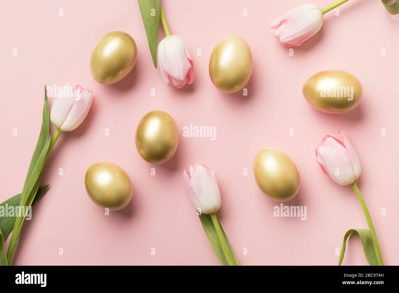 Easter golden eggs and pink tulips on pink paper background. Top view ...