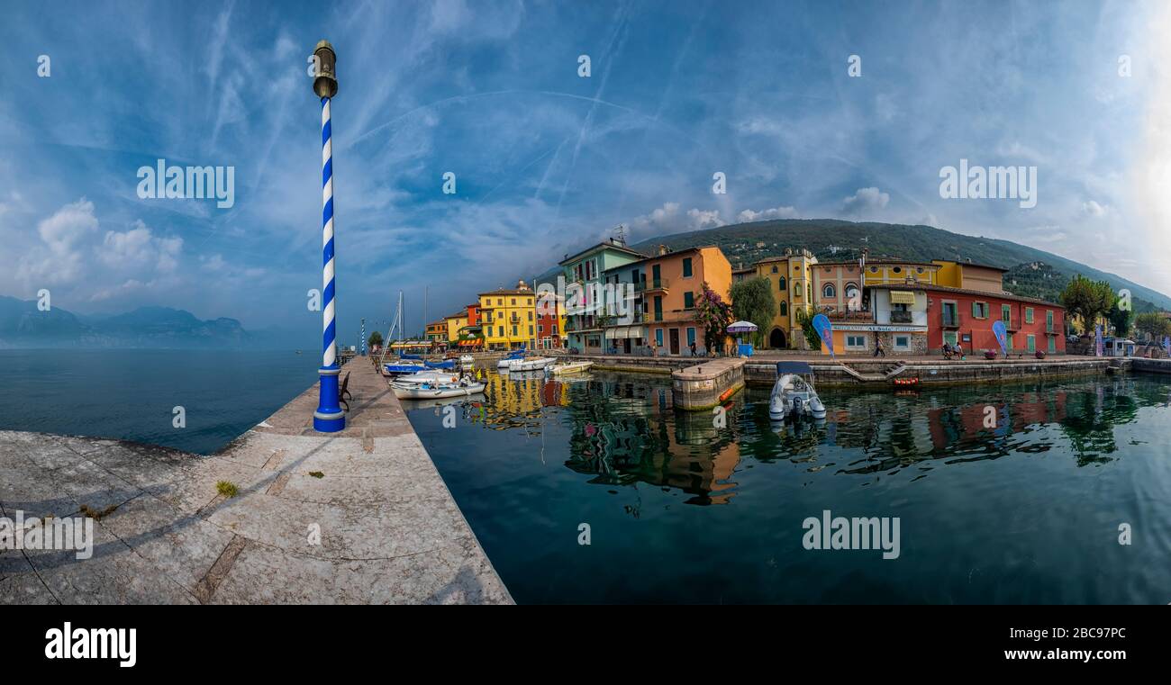 Lake Garda boardwalk with houses, tourists and boats in Torbole, Italy Stock Photo