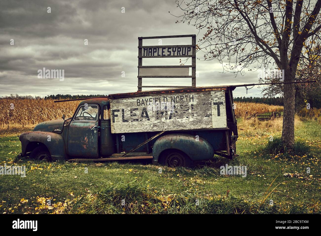 Old green abandoned rusty GMC truck being used as a flea market and maple syrup sign. Autumn scene. Stock Photo