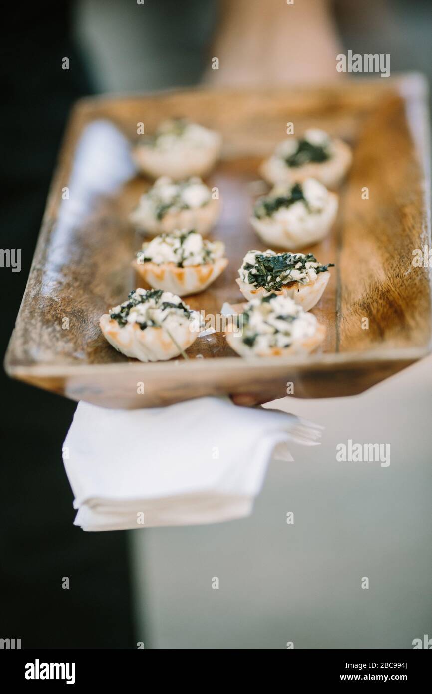 Appetizers on wood tray in server's hand at formal event Stock Photo