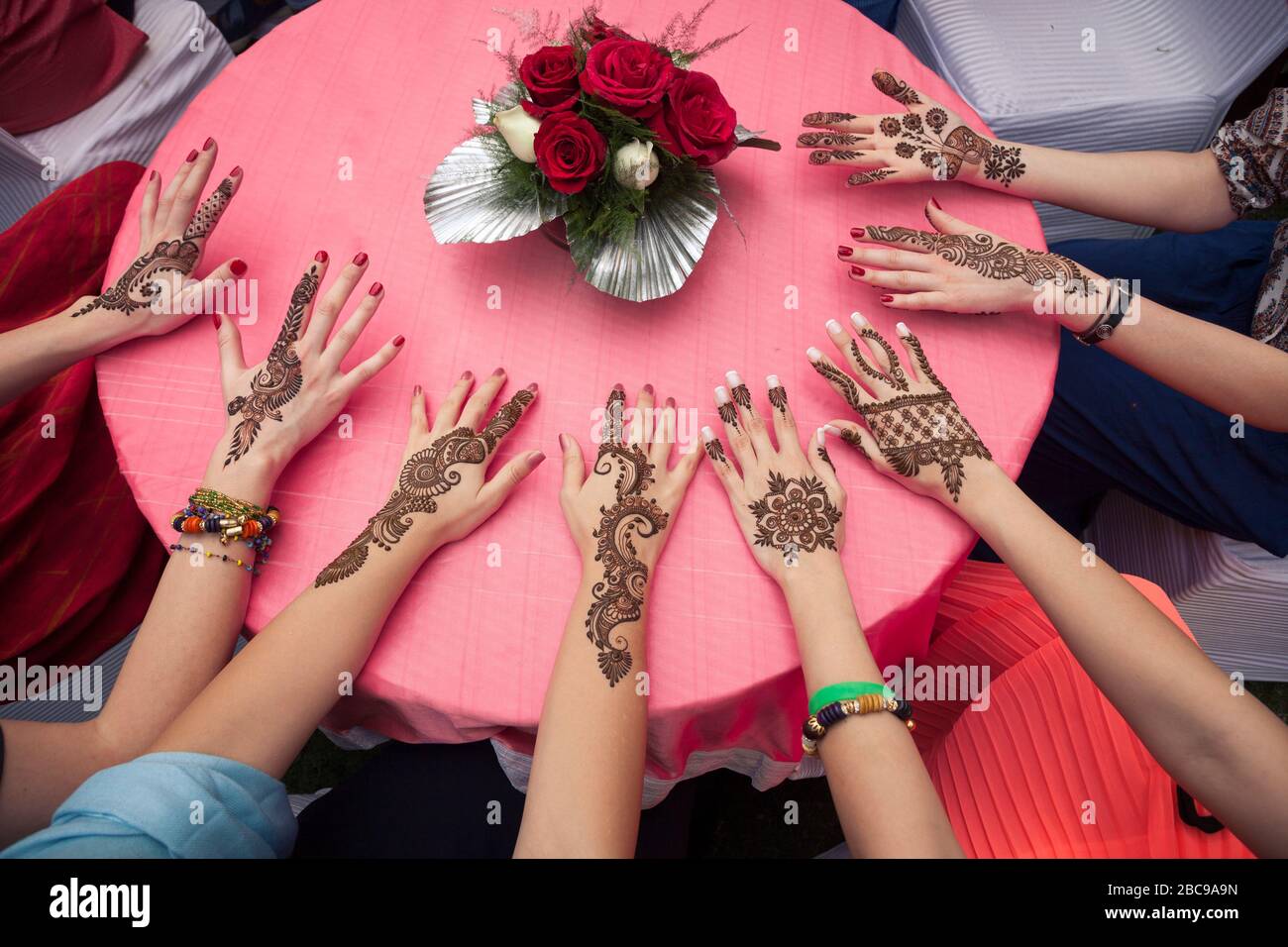 hands on table of young women with india hand painting mehendi henna Stock Photo