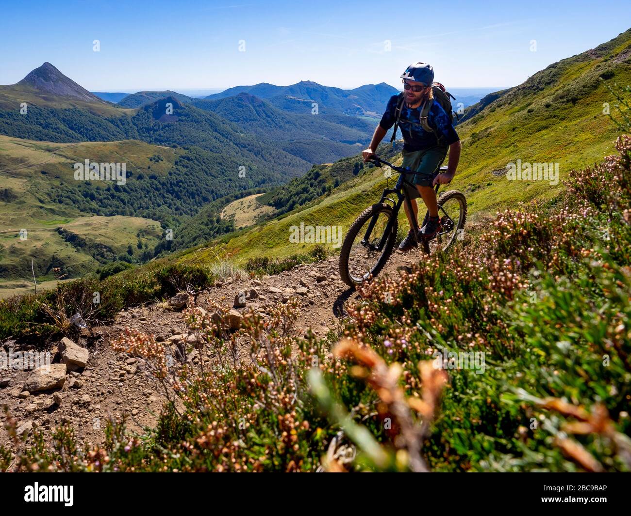 Mountain bikers on single trail at Col de Cabre, view of the Puy Griou