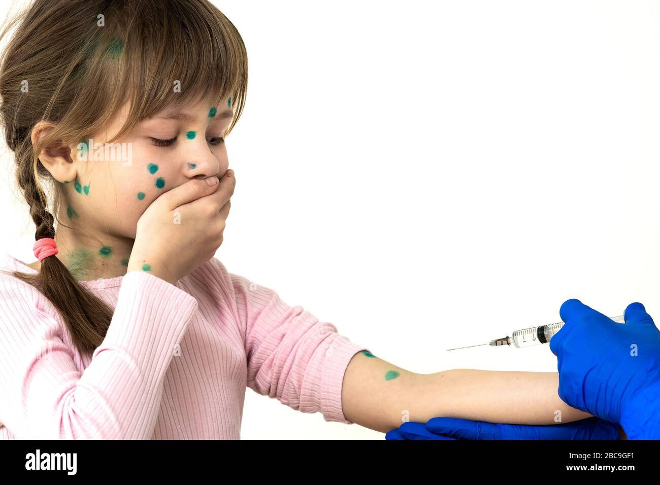 Doctor making vaccination injection to an afraid child girl sick with chickenpox, measles or rubella virus. Vaccination of children at school concept. Stock Photo