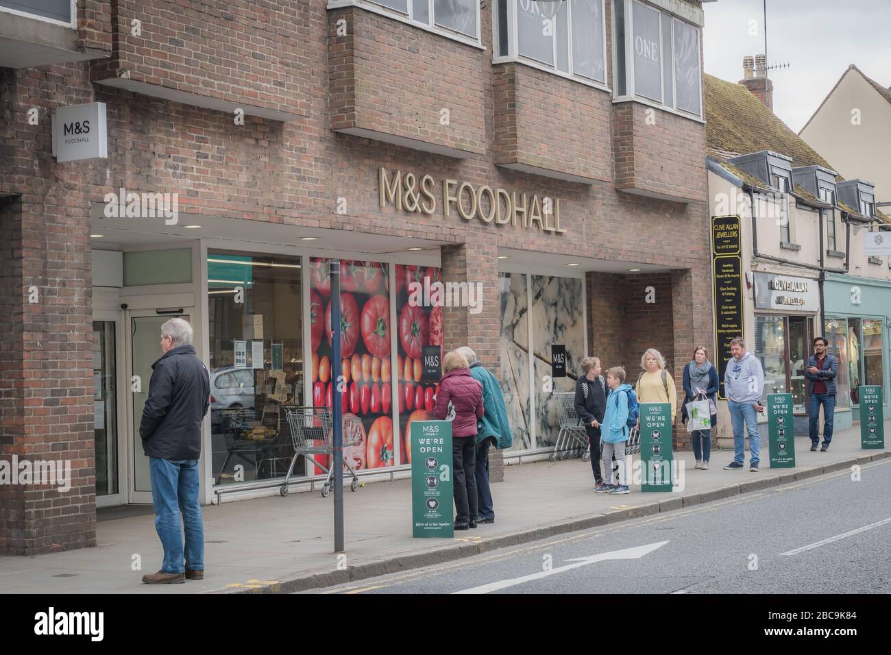 High Street, Reigate, Surrey, UK - April 3, 2020 - shoppers queueing outside M&S supermarket, maintaining social distancing to stop coronovirus spread Stock Photo