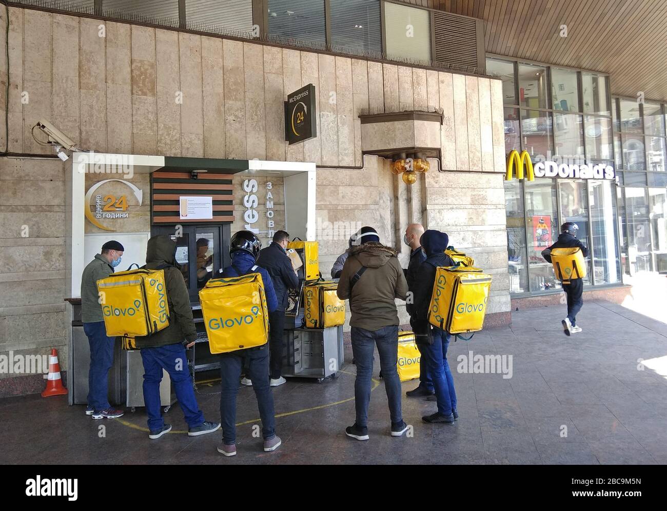 Kyiv, Ukraine - April 3, 2020: Couriers of Glovo Delivery Service waiting in a line at McDonalds Express during COVID-19 quarantine in Kyiv, when all restaurants work only in delivery mode Stock Photo