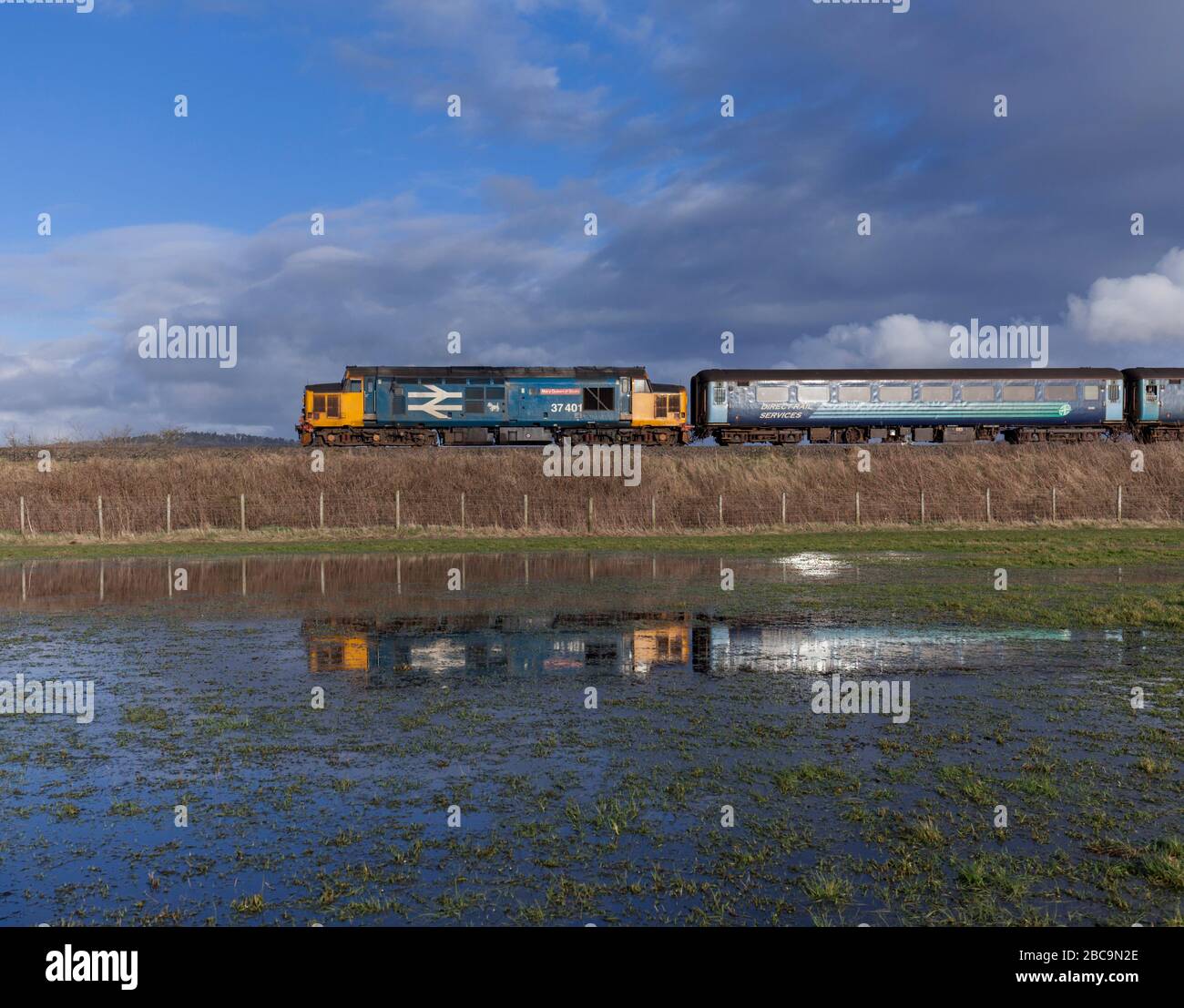 Direct Rail Services class 37 locomotive 37401 reflected in a flooded field while working a Northern Rail passenger service Stock Photo